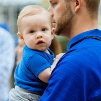 A man holding a baby at the Jamie Hosford Football Center dedication.